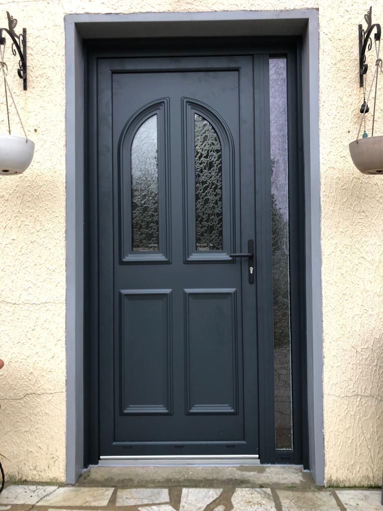Porte d'entrée gris avec un vitrage sur le côté.