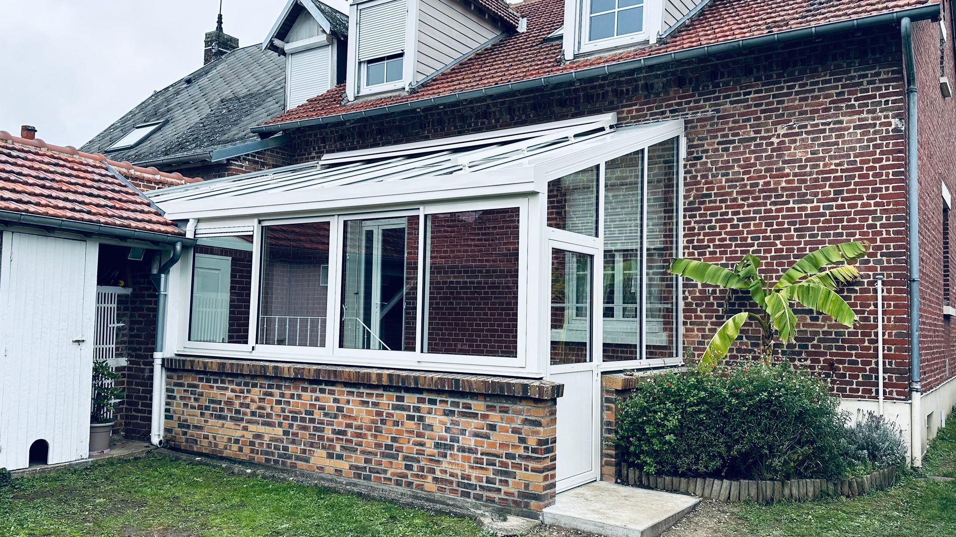 Une pergola blanche avec le muret de soubassement en briques.