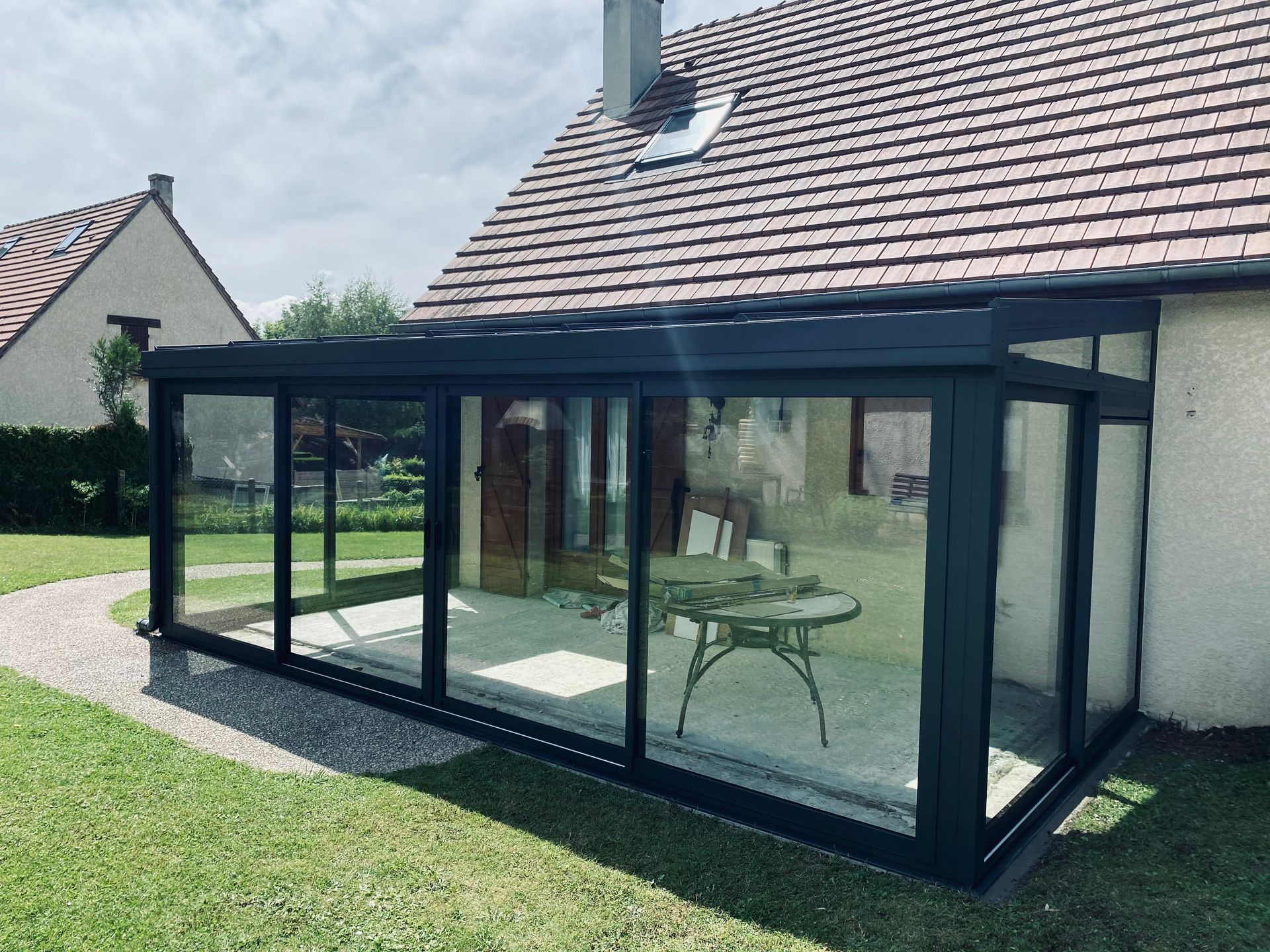 Vue sur une véranda avec parois vitrées, attenante à une maison.