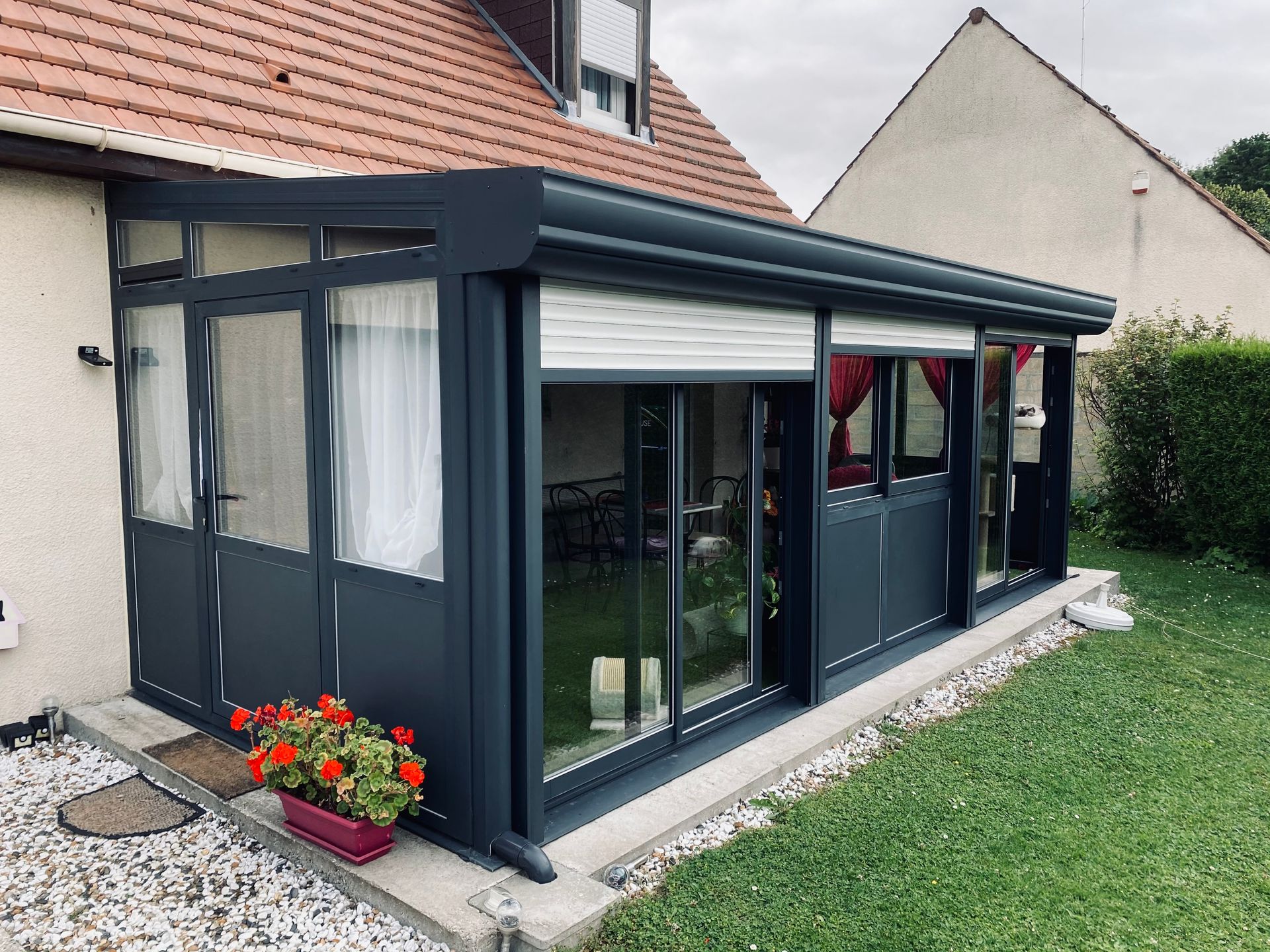 Une véranda avec des volets roulants ouverts.