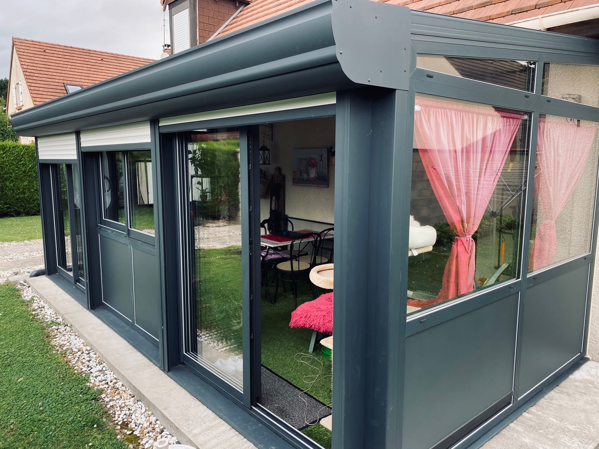 Vue sur le côté sur une véranda équipée d'une baie vitrée.