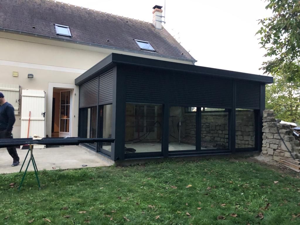 Véranda aluminium avec des volets roulants.