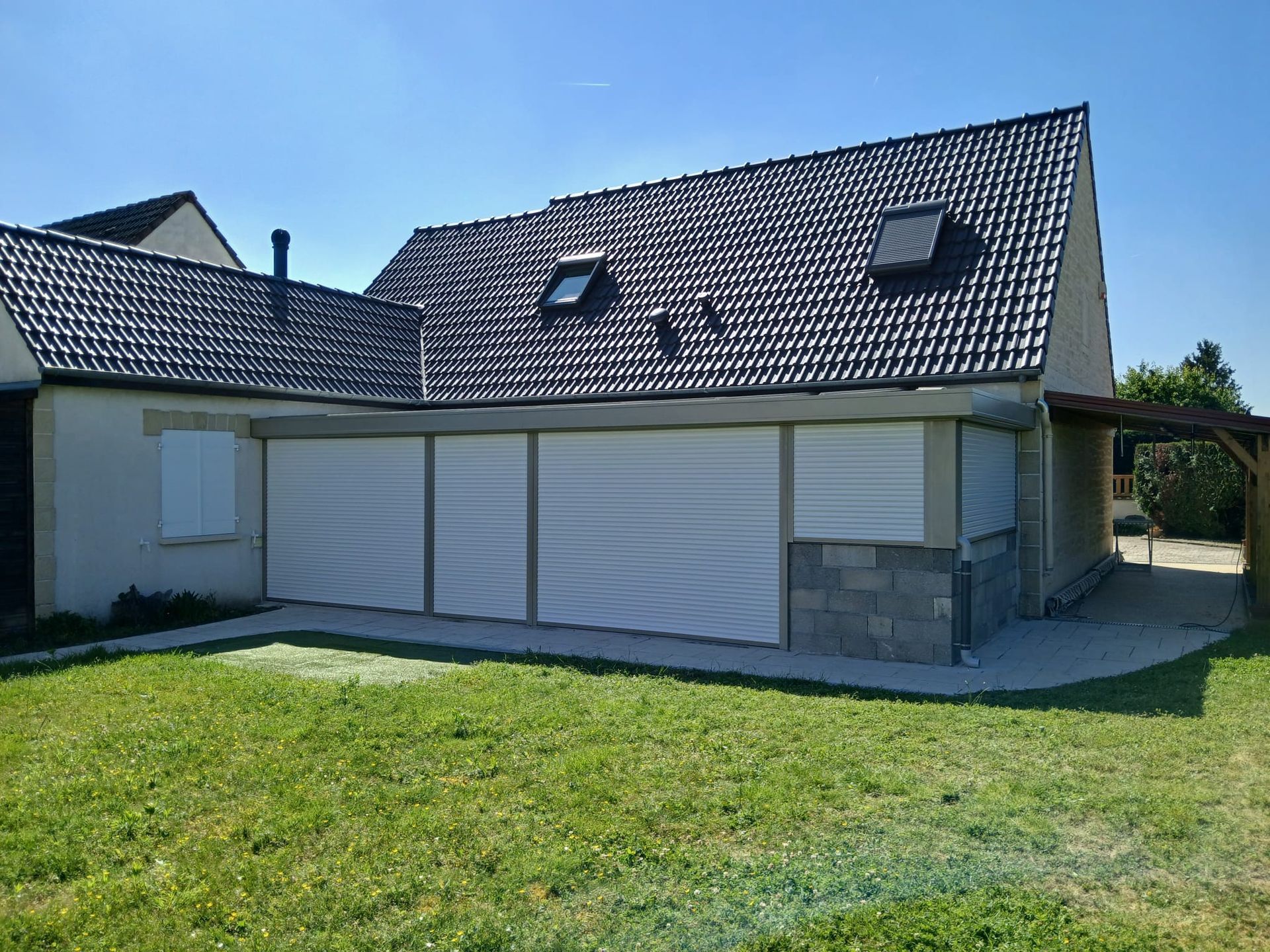Véranda attenante à la maison avec des stores fermés.