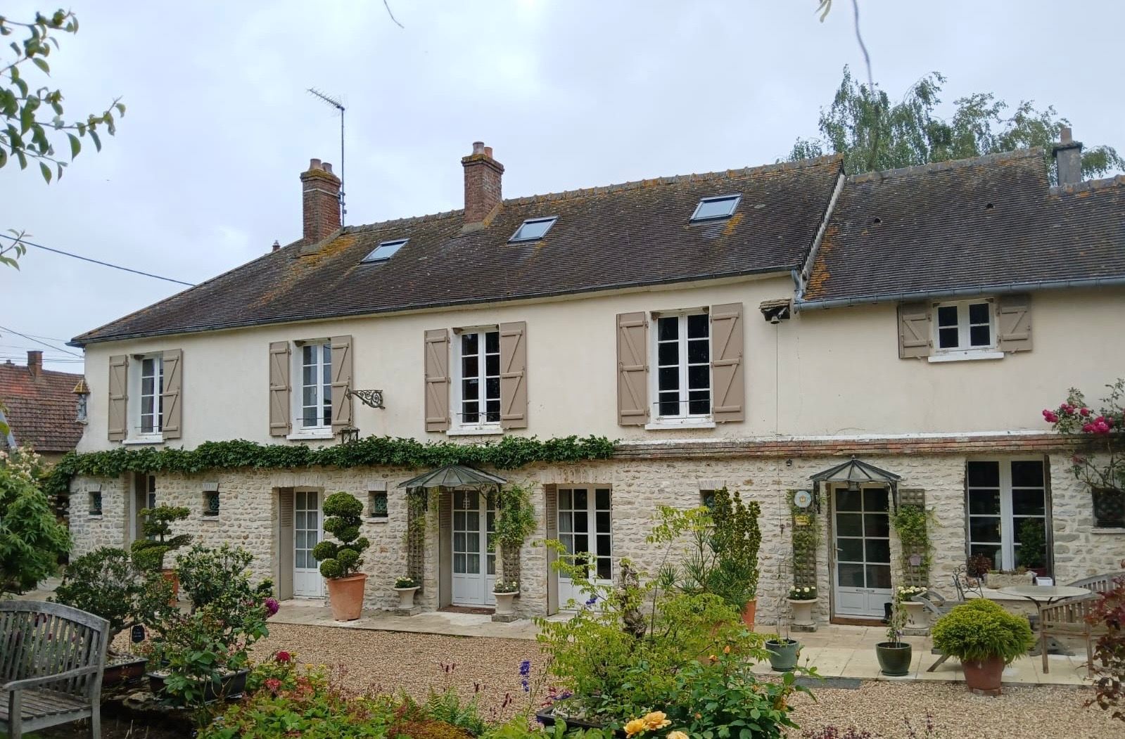 Façade d'une maison avec plusieurs fenêtres, portes-fenêtres et volets battants. 