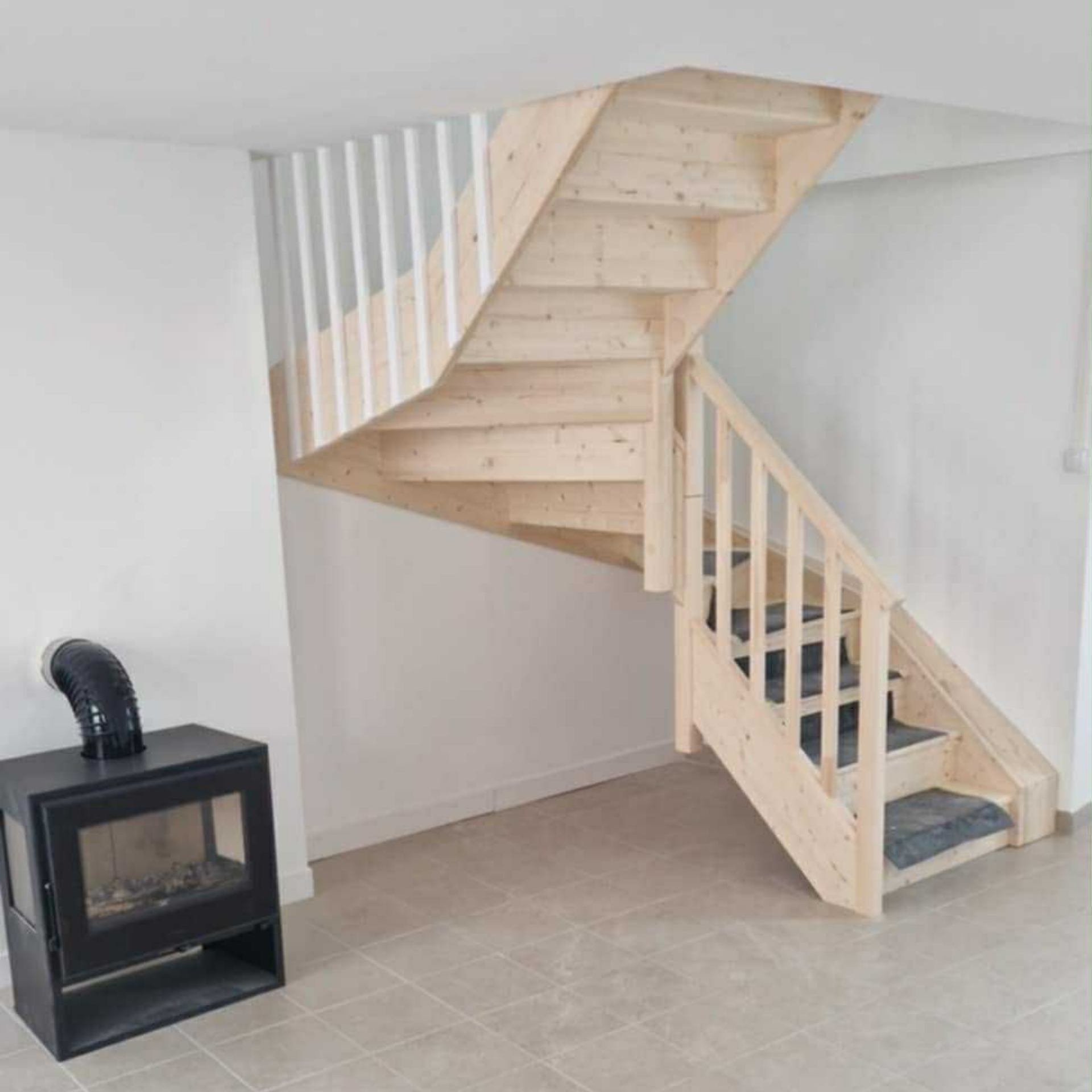 Un escalier en bois et une cheminée noire dans un salon.