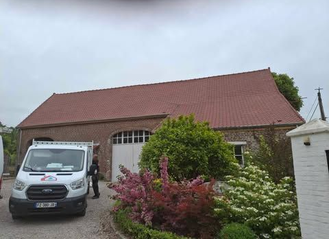 Un bâtiment en briques avec un toit de tuiles rouges et un camion de Entreprise Jérémy Martin.