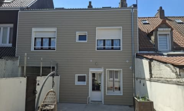 Extérieur de maison avec bardage beige, fenêtres, portes et volets.