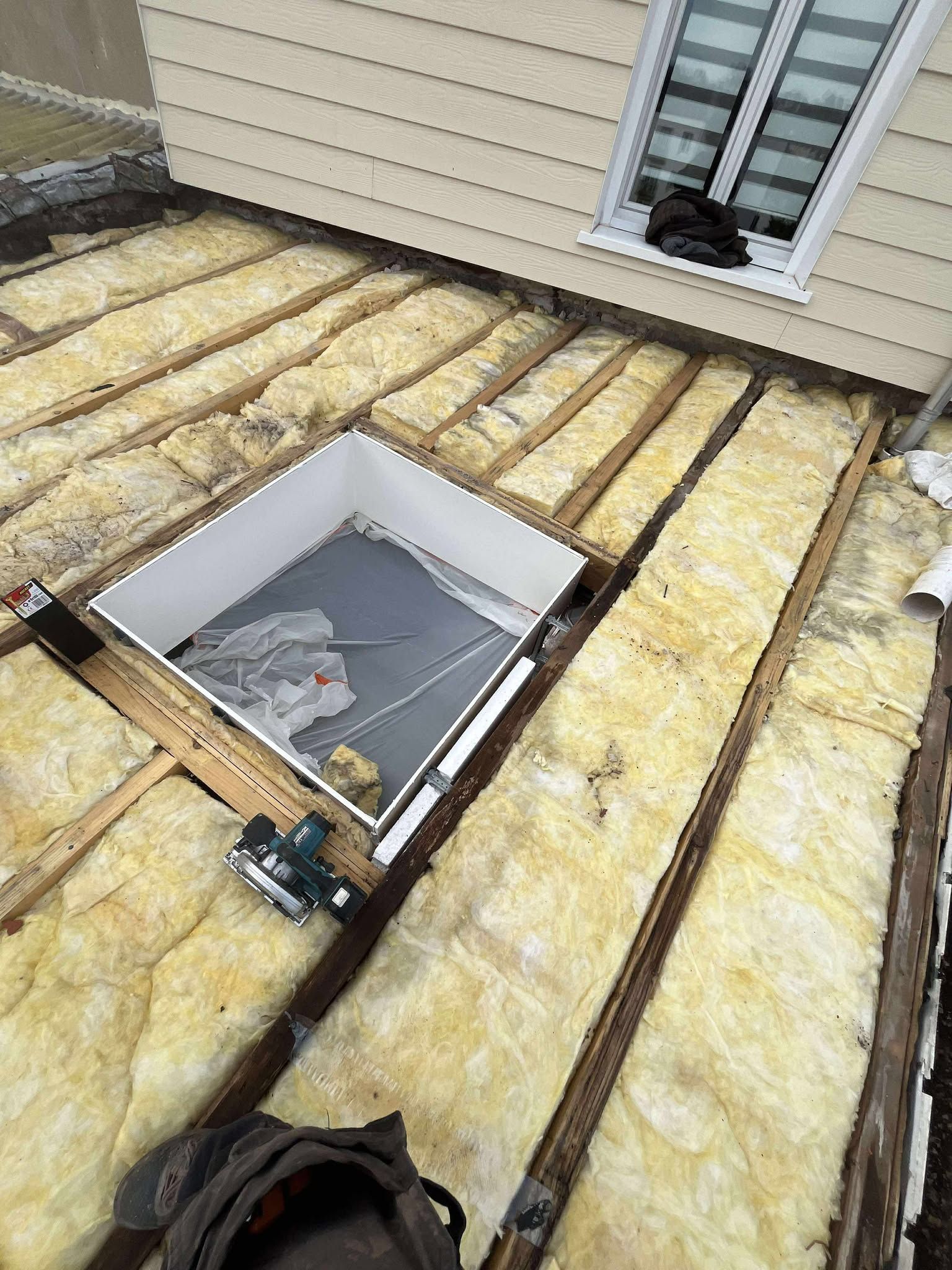 Maison avec deux parties de toiture : une noire, l'autre en rénovation.