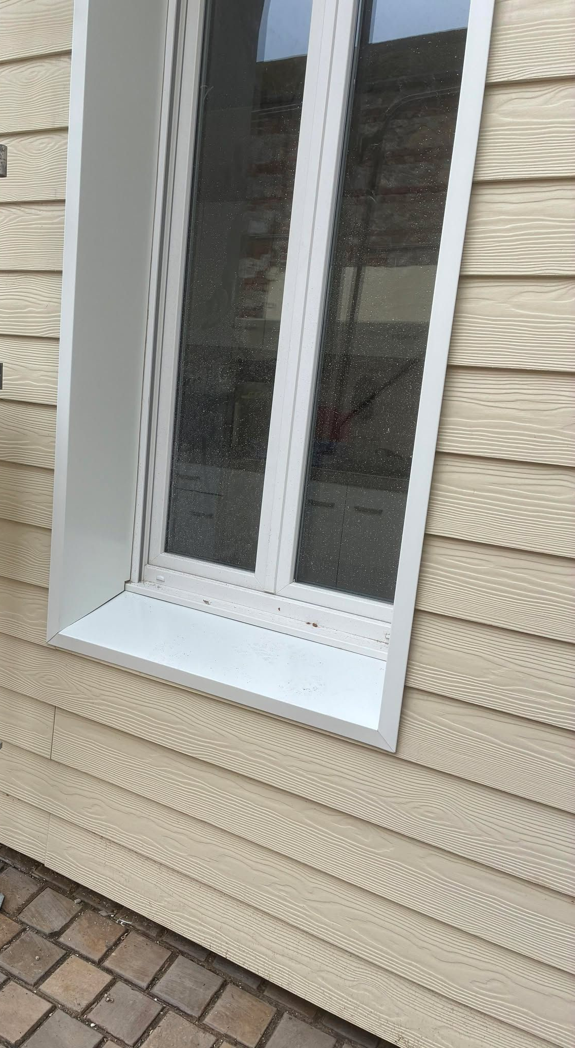 Fenêtre à cadre blanc sur un mur lambrissé beige.