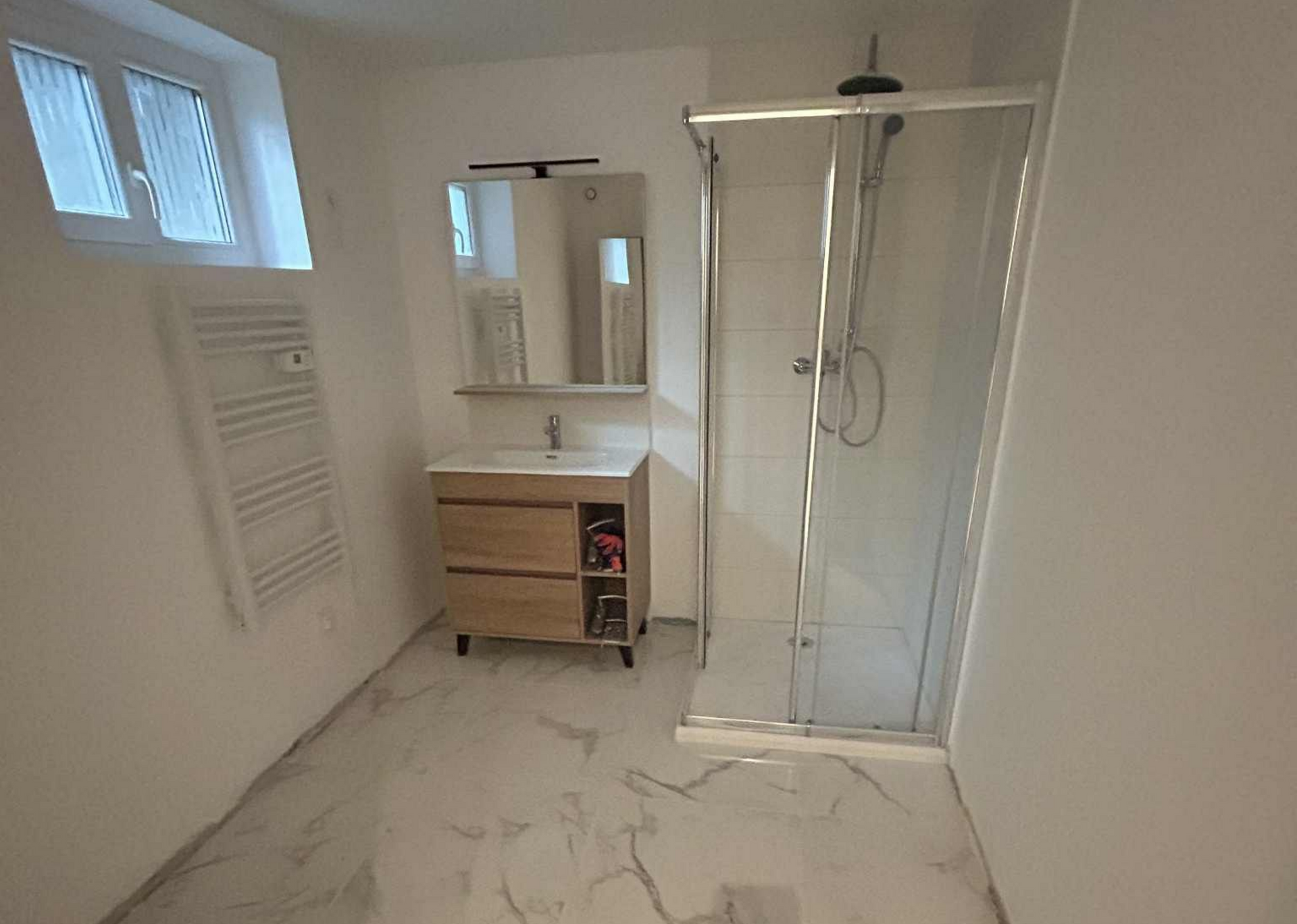 Salle de bains carrelée moderne avec douche à l'italienne, toilettes et lavabo.