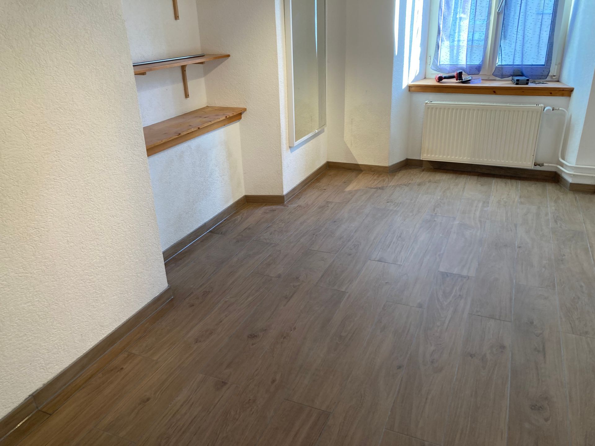 Une personne portant des gants de travail pose une dalle sur une allée.