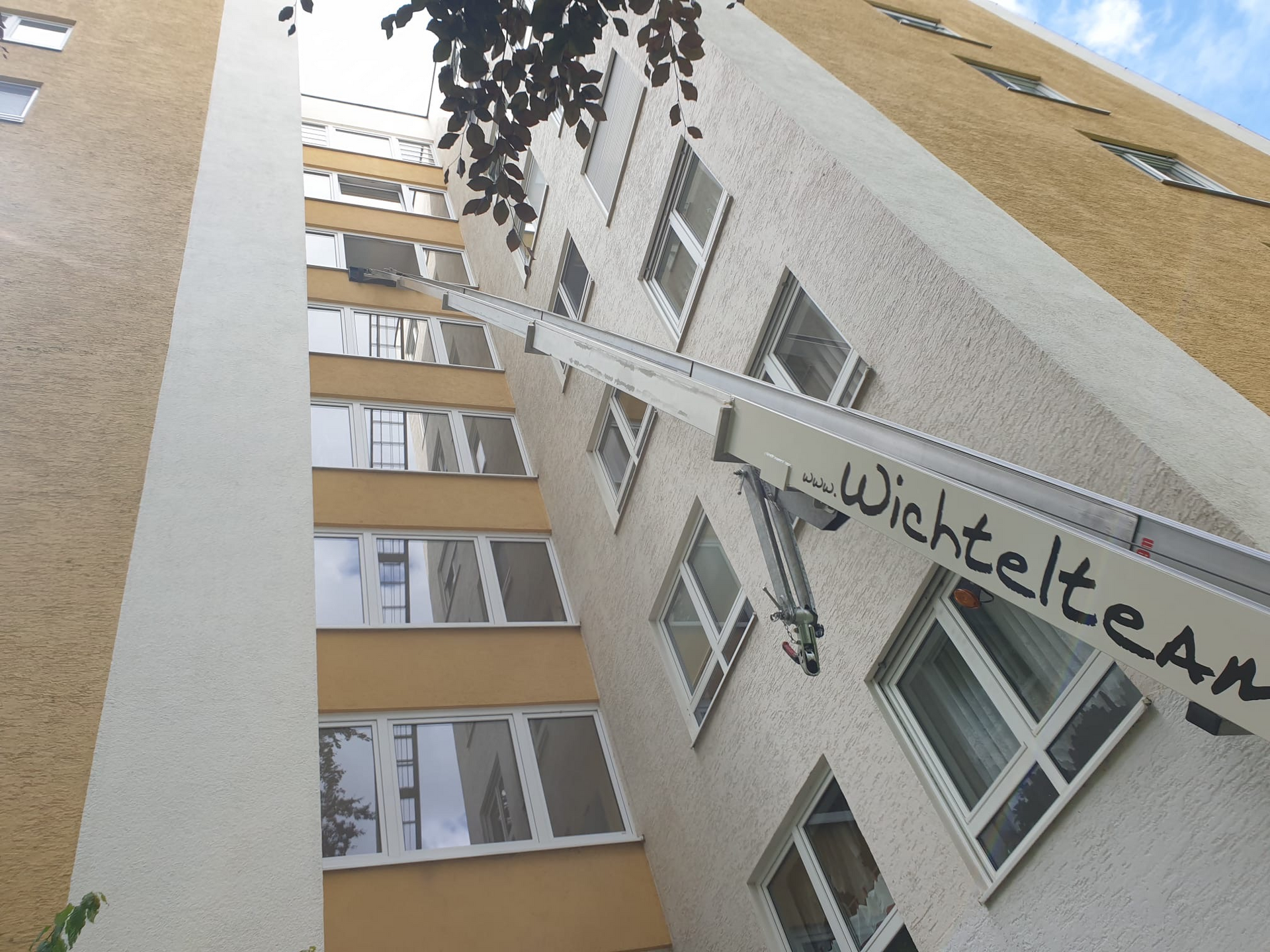 In einem Hochhaus befindet sich ein Gabelstapler, der einen Gegenstand transportiert. Der Gabelstaplerarm befindet sich neben den Fenstern.