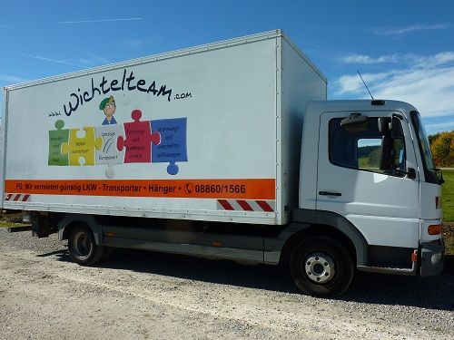 Weißer Kastenwagen mit dem Logo „Wichtelteam“ an der Seite, im Freien unter blauem Himmel geparkt.