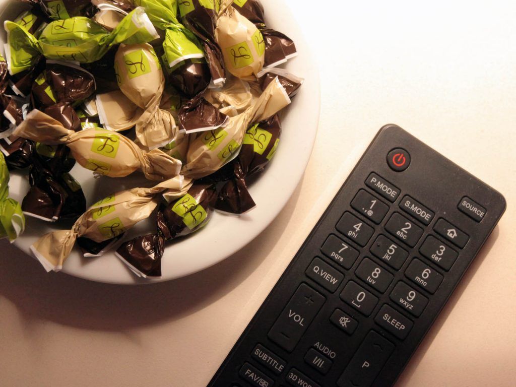Une assiette rempli de bonbon à côté d'une télécommande.