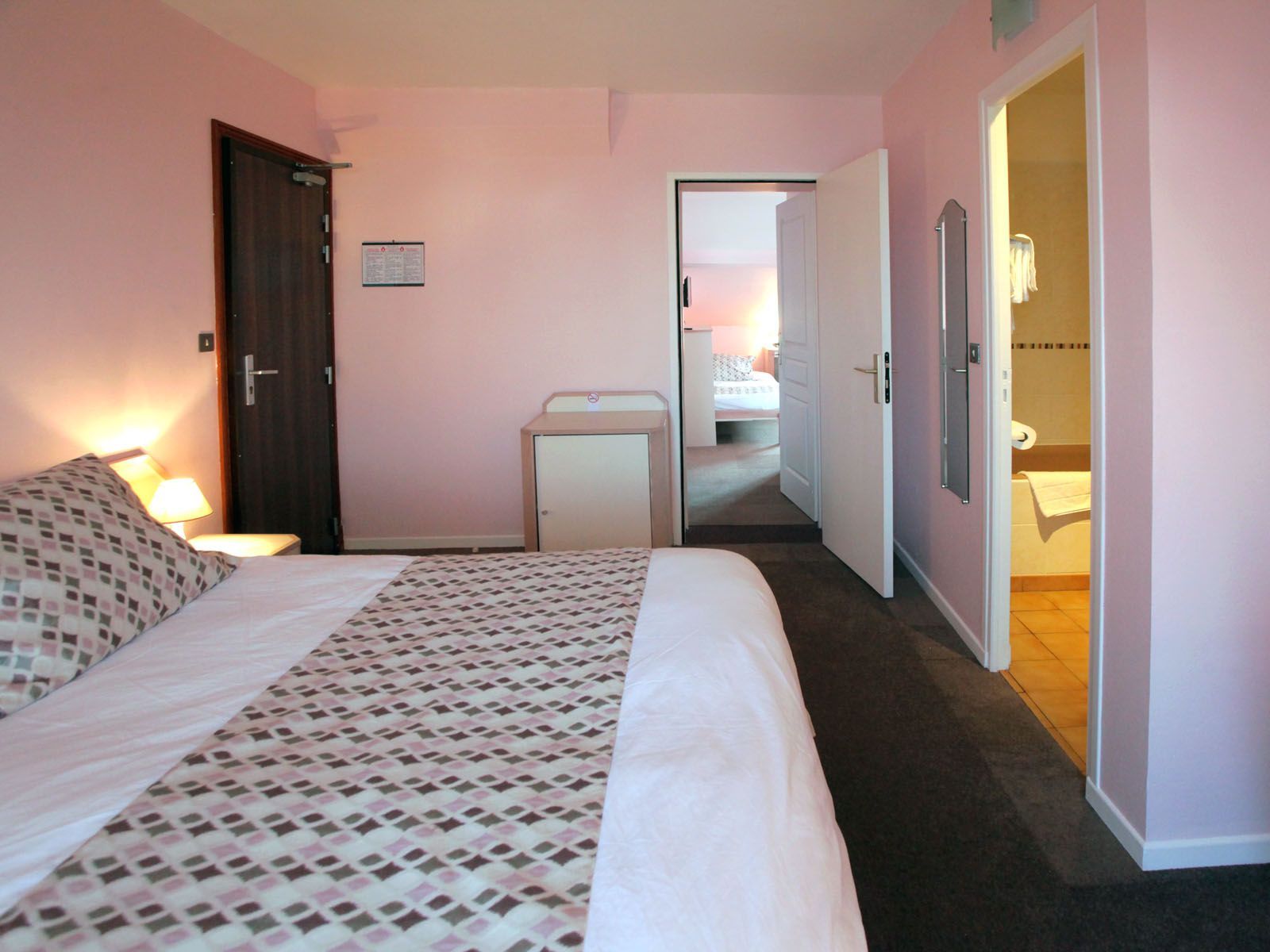Une chambre d'hotel aux murs rose.