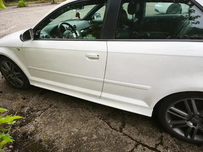 Audi blanco estacionado sobre una superficie de hormigón. Vista lateral, llantas gris oscuro, 