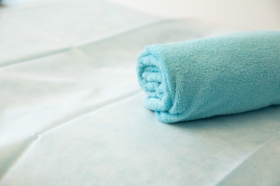 Gerolltes türkisfarbenes Handtuch auf hellblauem Untergrund.