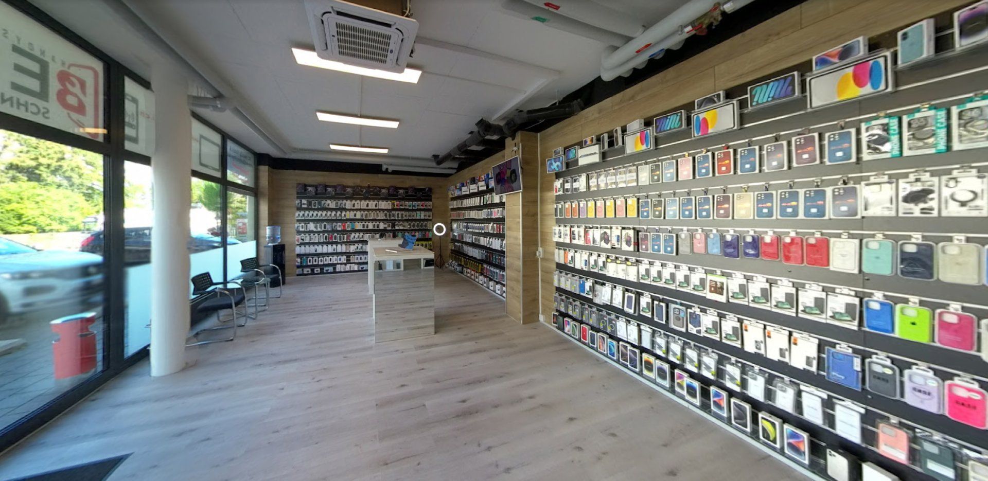 Innenansicht eines Einzelhandelsgeschäfts mit Regalen voller Handyhüllen. Weisser Boden, natürliches Licht.