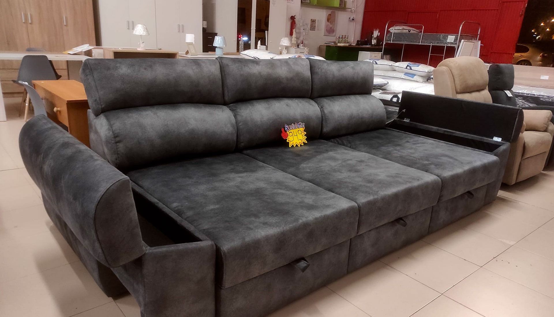 Un gran sofá gris está en una habitación con otros muebles.