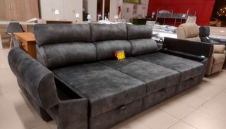 Un gran sofá gris está en una habitación con otros muebles.
