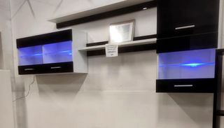 Una pared blanca con gabinetes negros y luces azules.