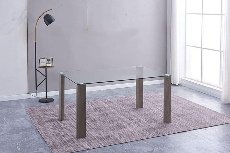 Una mesa de comedor de vidrio está colocada encima de una alfombra en una sala de estar.