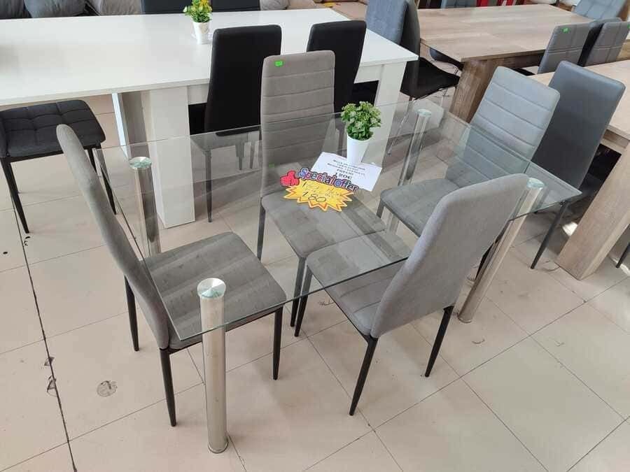 Una mesa de comedor de cristal con sillas grises en una tienda.