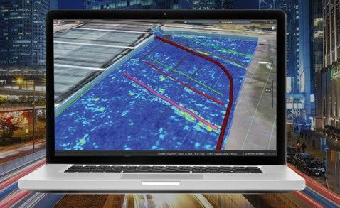 Laptop mit blauer Karte und roten Routenlinien vor dem Hintergrund einer Stadtstraße