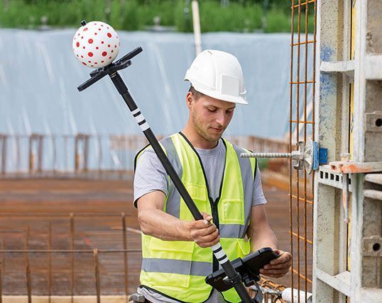 Ein Bauarbeiter benutzt auf einer Baustelle ein Tablet.