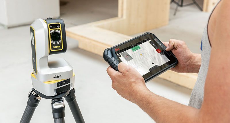 Ein Mann hält ein Tablet vor eine Kamera auf einem Stativ.