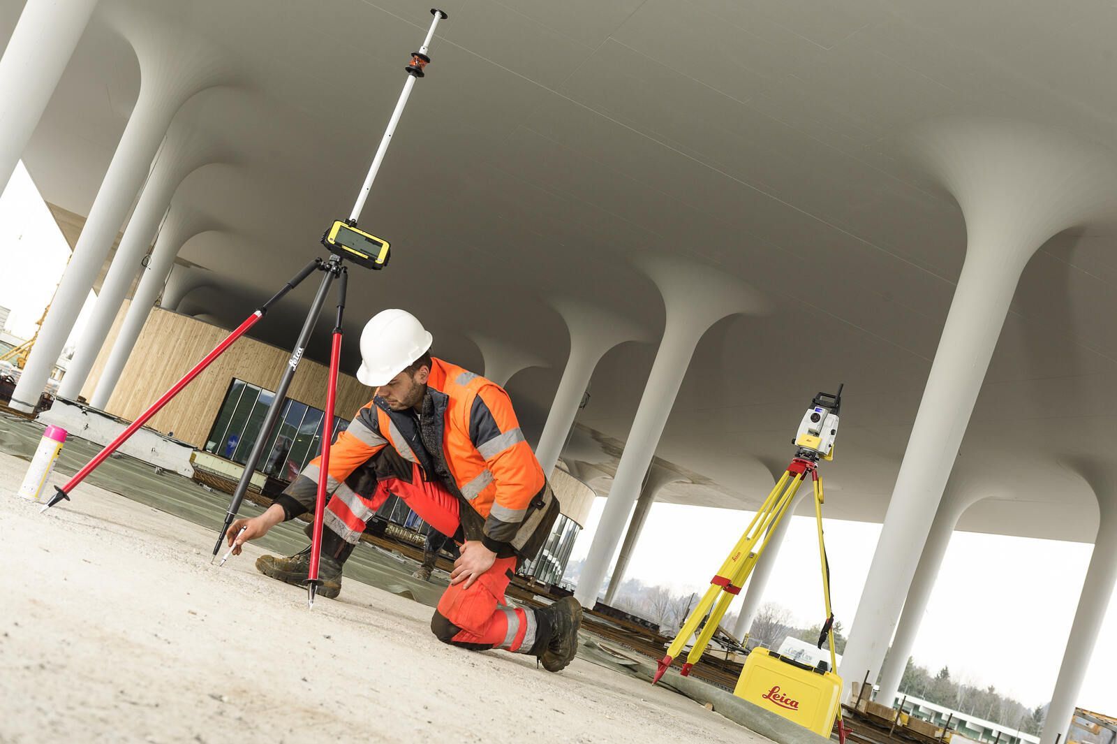 Ein Mann kniet mit einem Stativ auf dem Boden.