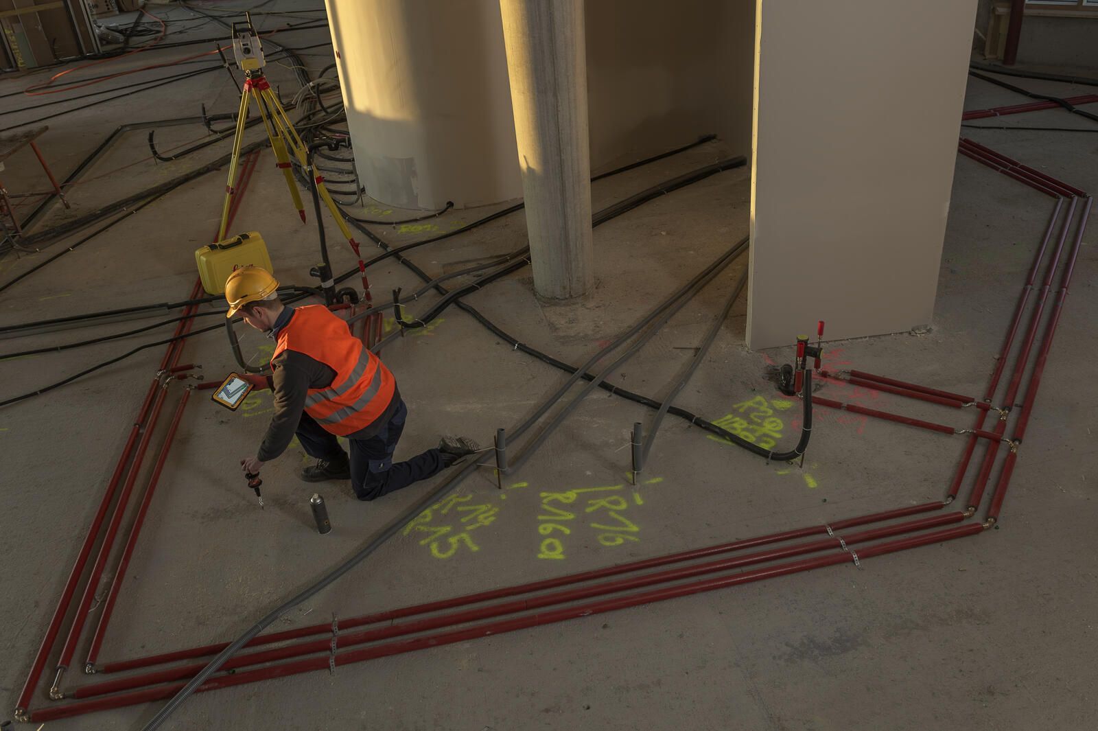 Ein Bauarbeiter kniet auf dem Boden eines Gebäudes.