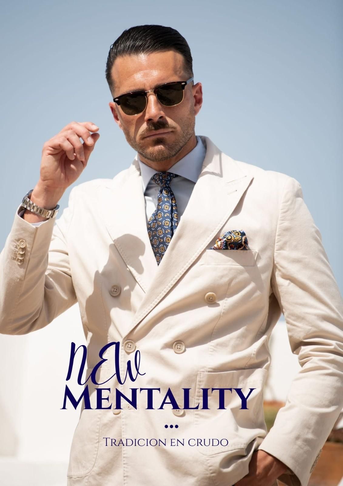 Un hombre lleva una chaqueta cruzada beige, una camisa azul claro 