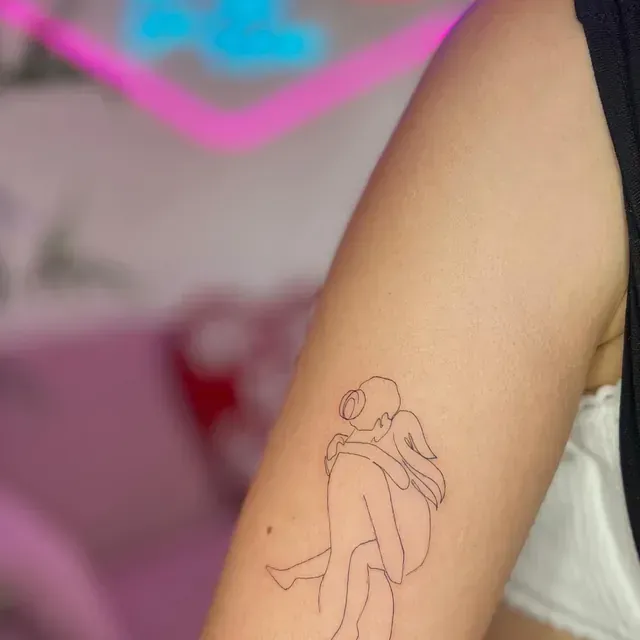 Tatuaje de arte lineal de figuras abrazándose en el brazo de una persona.