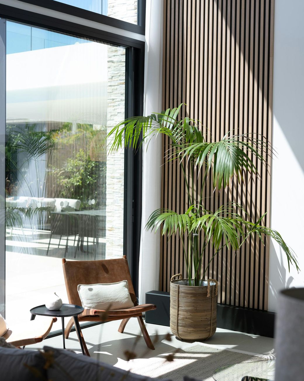 Una sala de estar con una silla, una mesa y una planta en maceta.