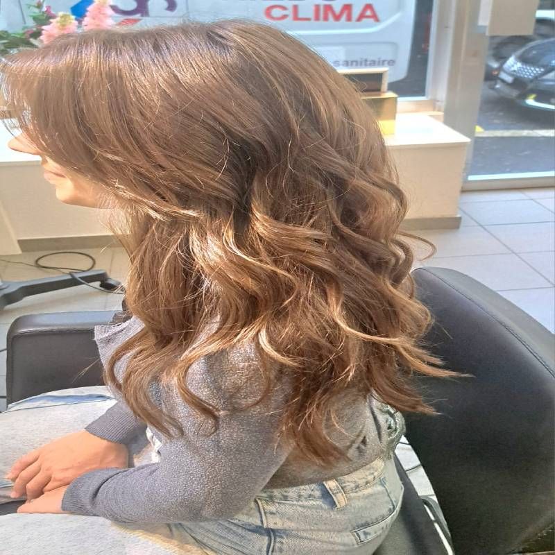 Une femme aux cheveux longs est assise sur une chaise devant une camionnette sur laquelle est écrit clima