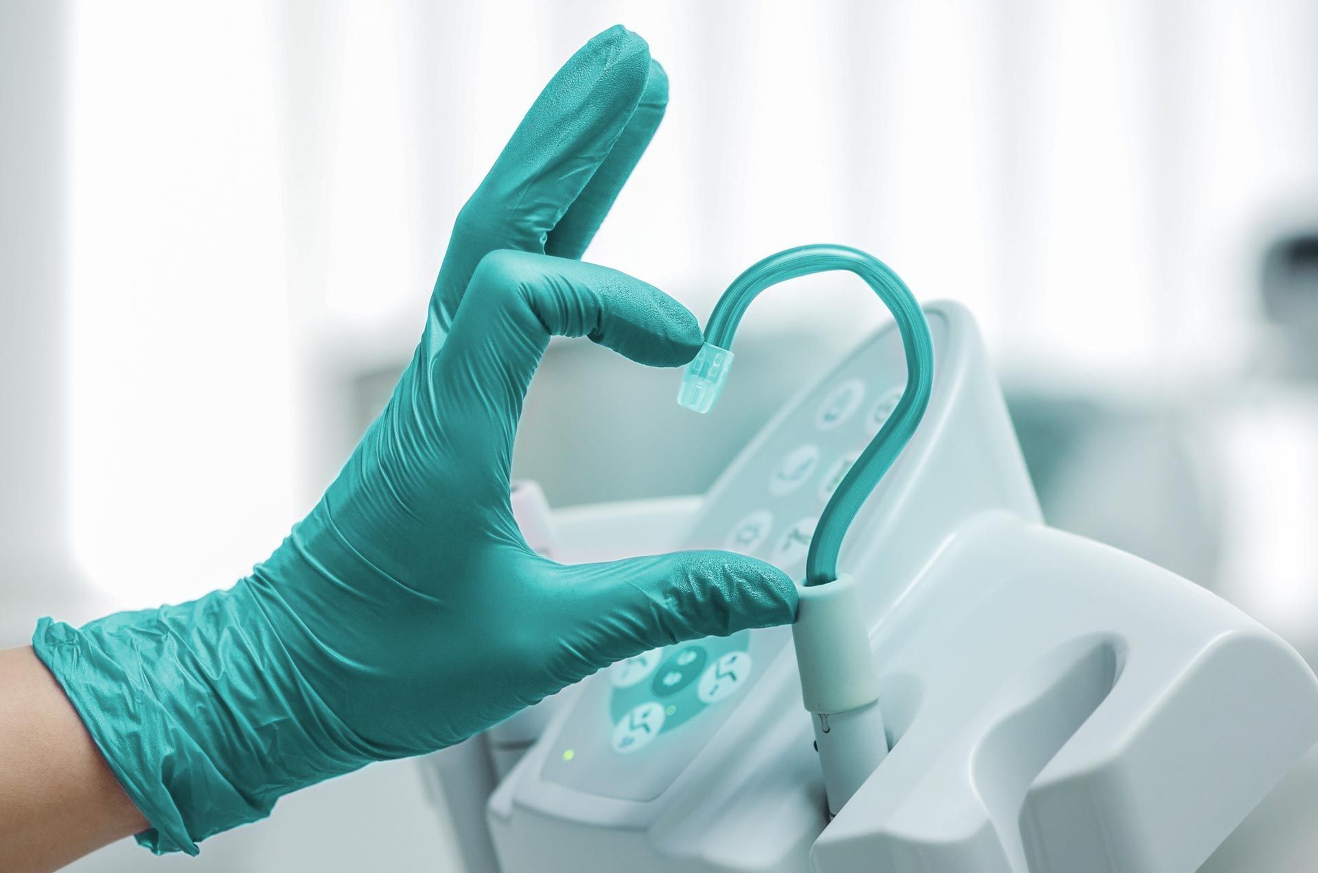 Eine Hand formt mit einem Zahnarzttool ein Herz