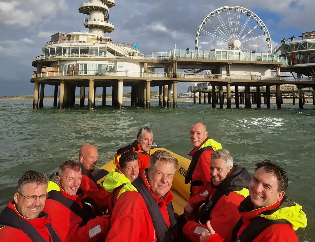 Een groep mannen vaart in een bootje door het water, met op de achtergrond een reuzenrad.