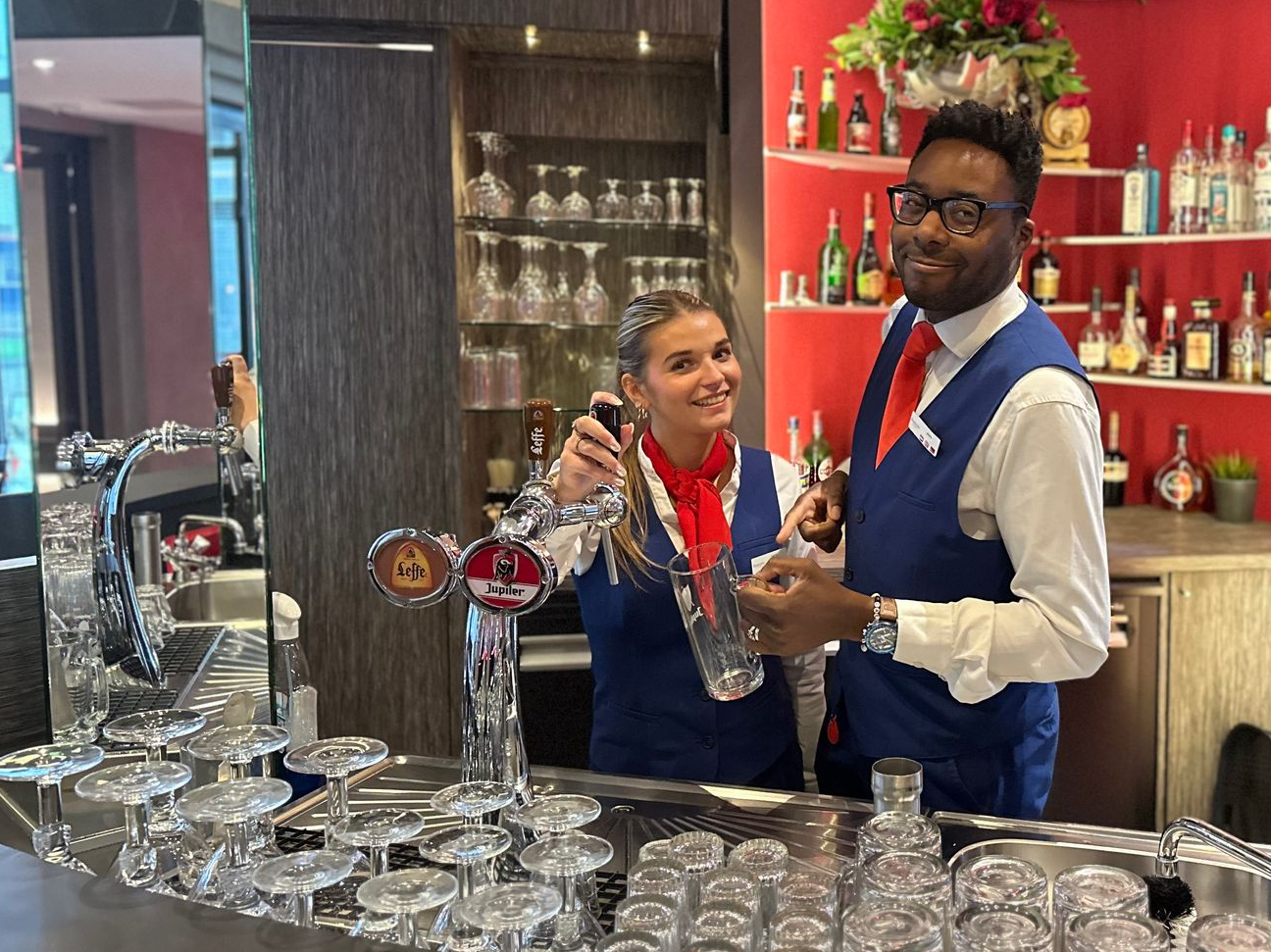 Een man staat achter een bar en maakt een drankje.