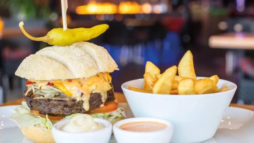 A hamburger and french fries are on a plate on a table.