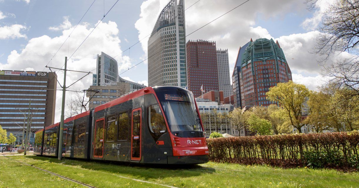 Een trein rijdt over een spoor voor de skyline van een stad.