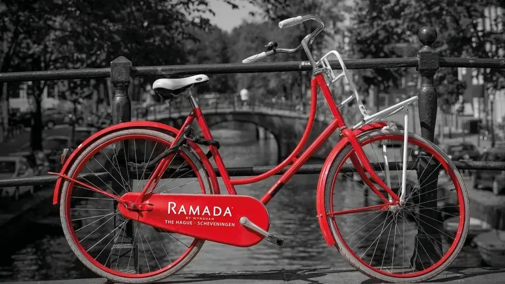 Een rode fiets staat geparkeerd op een brug over een rivier.