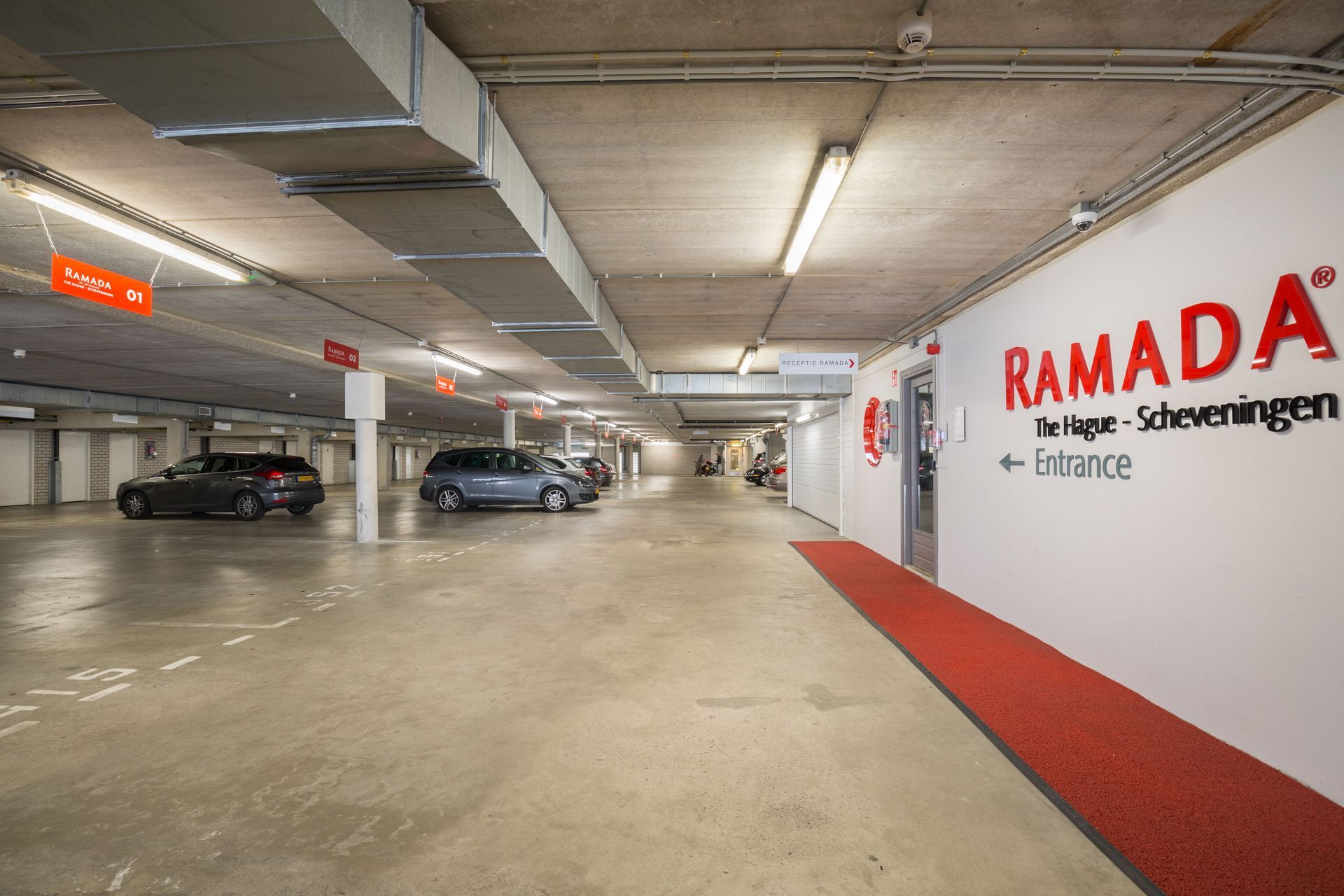 Een parkeergarage met geparkeerde auto's en een rode loper.