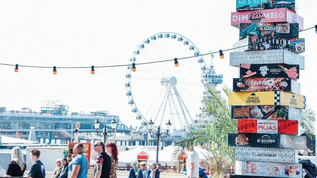 A group of people are standing in front of a ferris wheel.