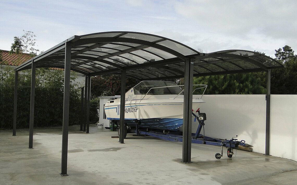 Bateau sur remorque abrité sous un carport.