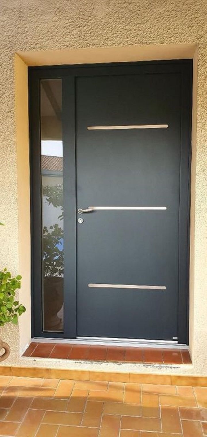 Une porte d'entrée grise moderne avec une fenêtre latérale et des poignées horizontales argentées.