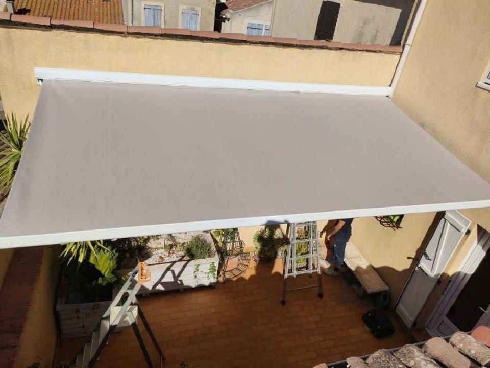 Un auvent beige déployé au-dessus d'une terrasse.