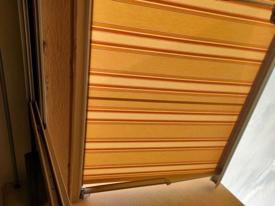 Auvent à rayures jaunes et brunes au-dessus d'une fenêtre.