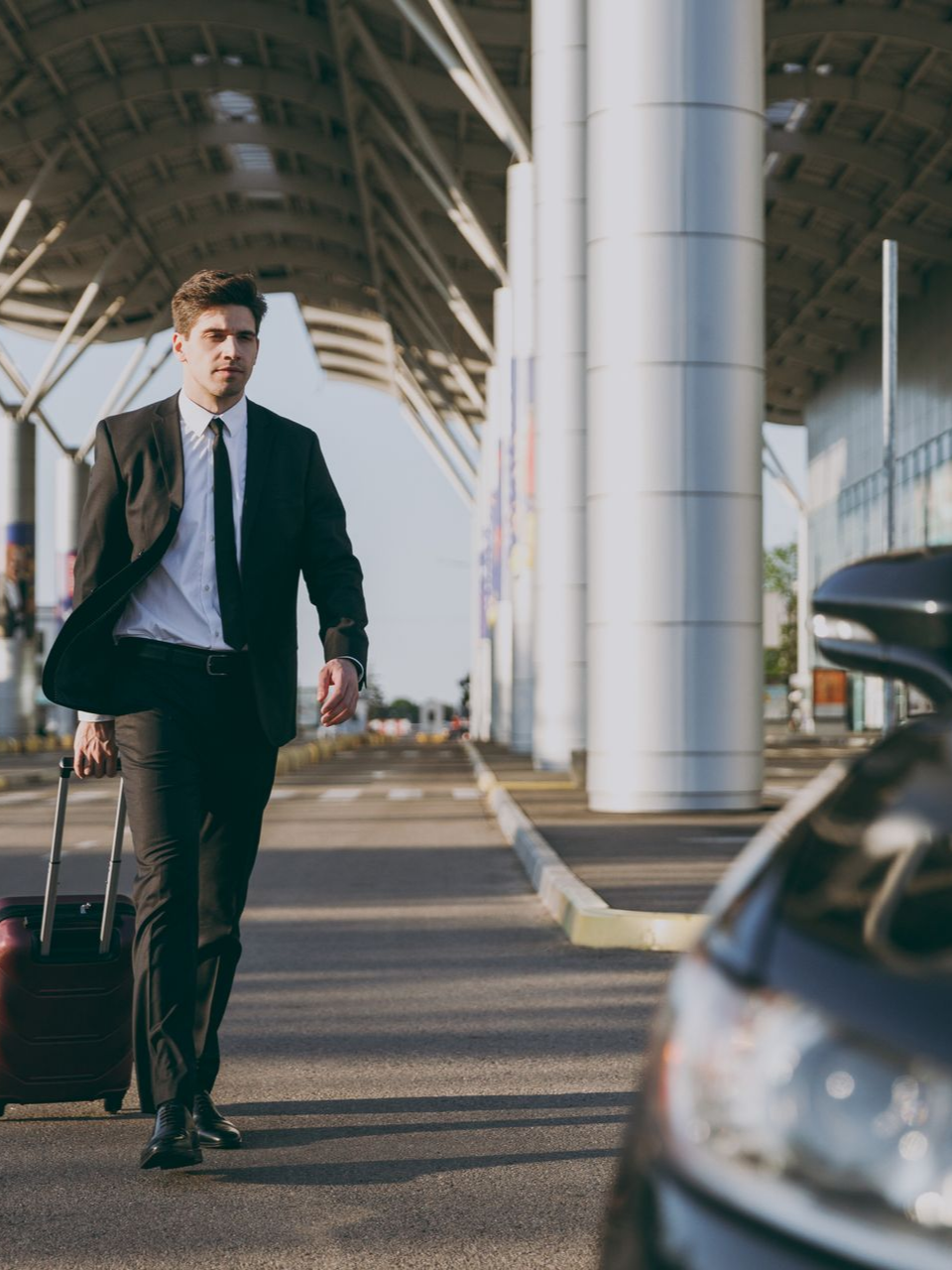 Un homme en costume marchant vers une voiture avec son bagage