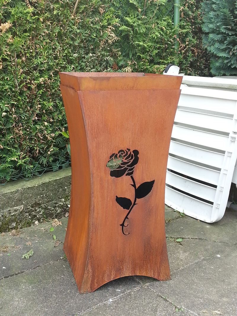 Eine Holzvase mit einer Rose darauf steht auf einem Gehweg.